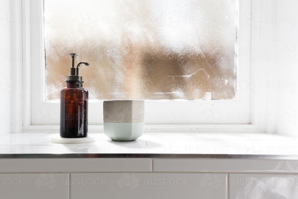Bathroom soap dispenser and pot on window ledge with background of negative space horizontal - Australian Stock Image