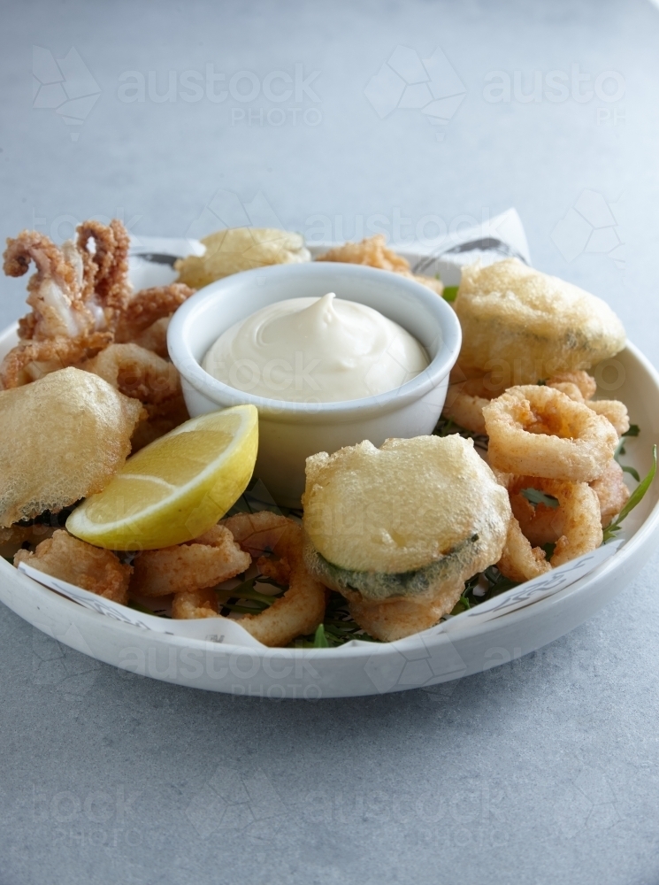 Image of Battered deep fried seafood and vegetables on plate with dip