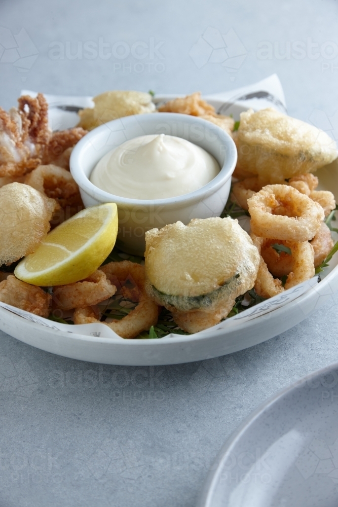 Battered deep fried seafood and vegetables on plate with dip - Australian Stock Image