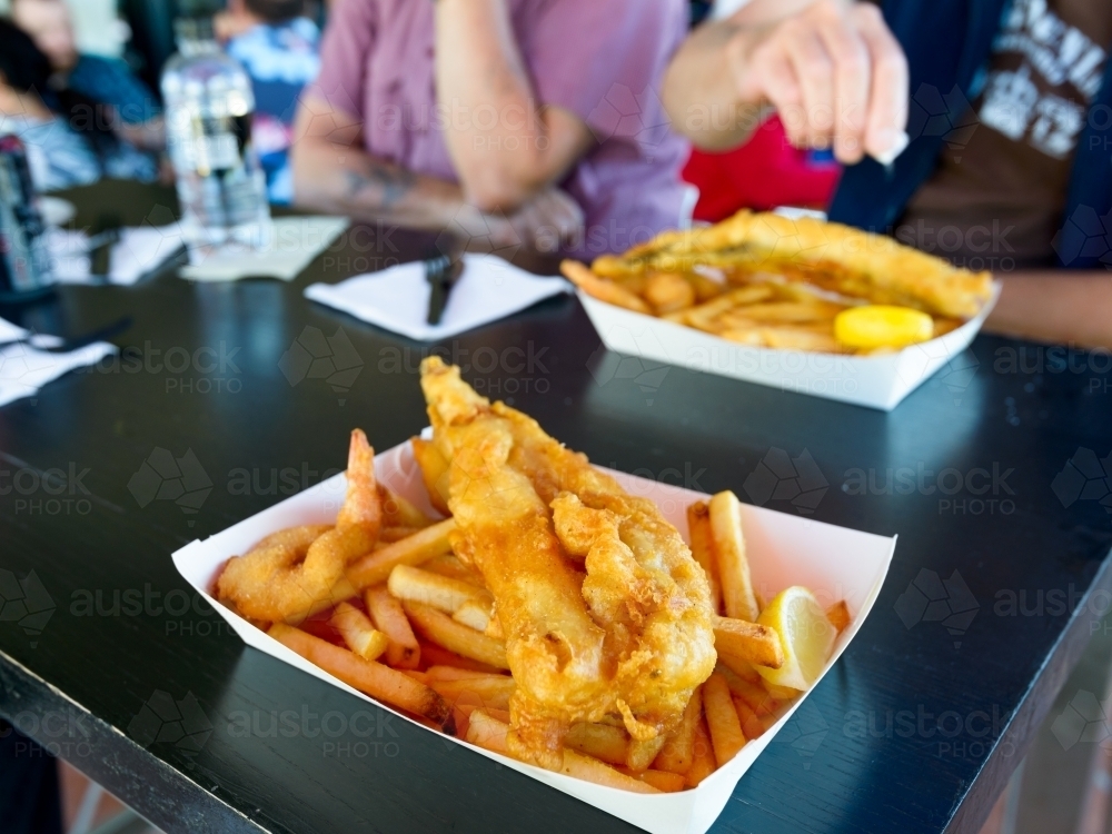 Battered Fish and chips with people blurred in the background - Australian Stock Image