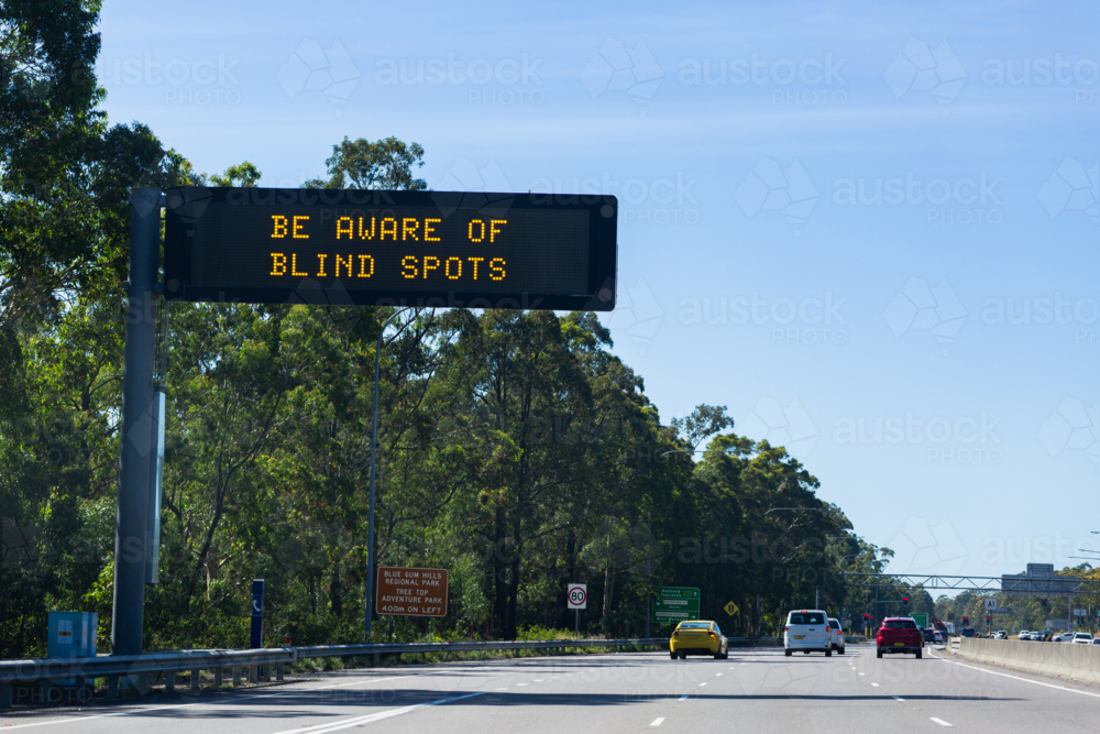 be aware of blind spots warning on digital signage above highway road - Australian Stock Image
