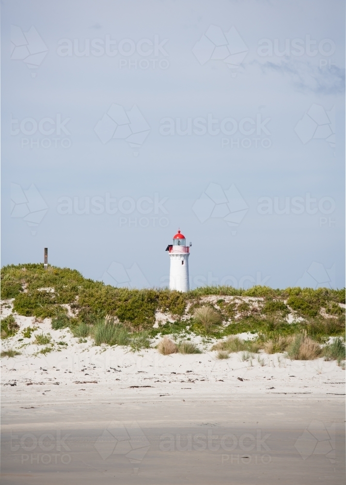 beach and sand dune with lighthouse in background - Australian Stock Image