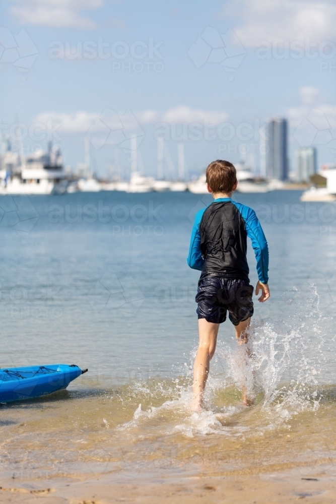 Beach Fun, boy splashing through water - Australian Stock Image