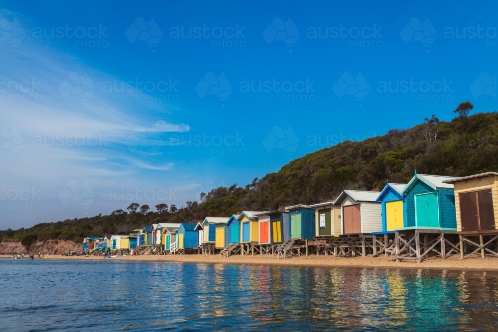 Beach huts at Mt Martha with water in the foreground and people on the beach - Australian Stock Image