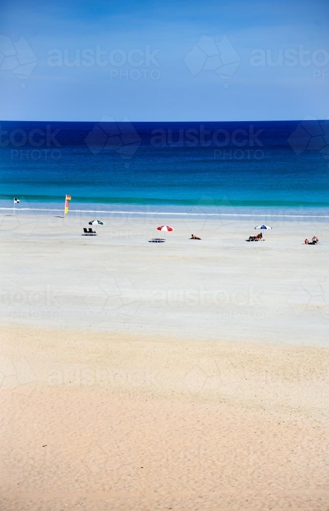 Beach scene with beach umbrellas and blue water - Australian Stock Image