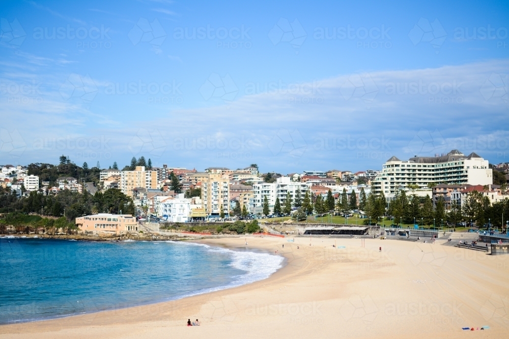 Beach that is almost empty, with buildings and trees in the background - Australian Stock Image