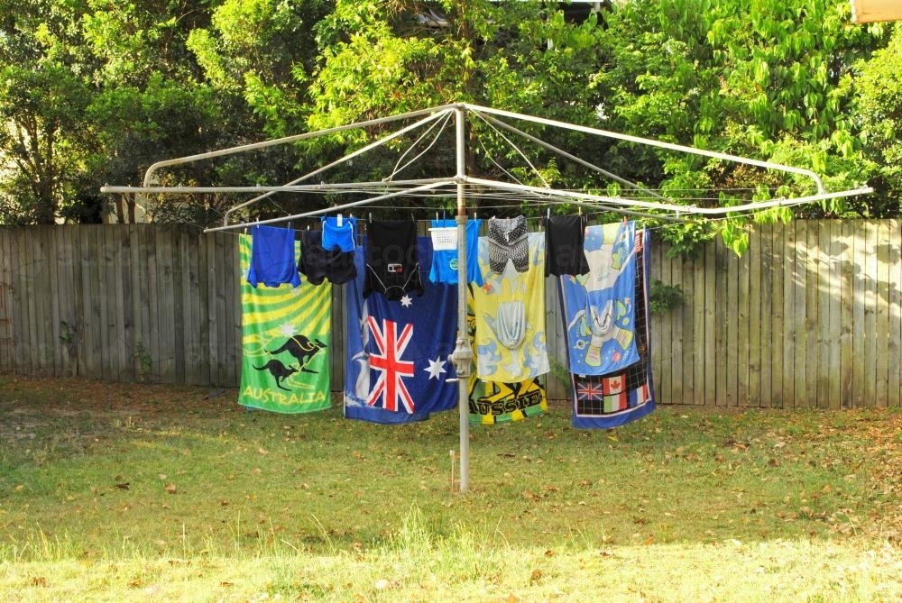 Beach towels and swimwear are hanging on a Hills Hoist in a suburban garden - Australian Stock Image