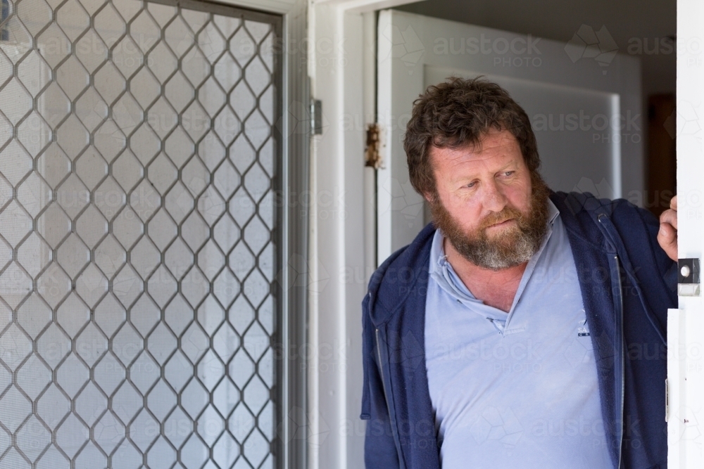 Bearded man looking out of doorway - Australian Stock Image