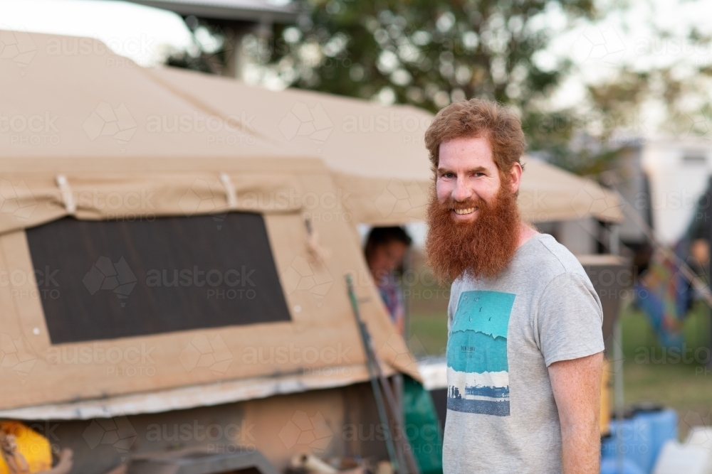 Bearded man near camper trailer in campground - Australian Stock Image