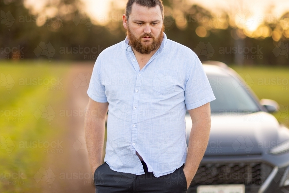 bearded man outdoors in front of car on rural track - Australian Stock Image