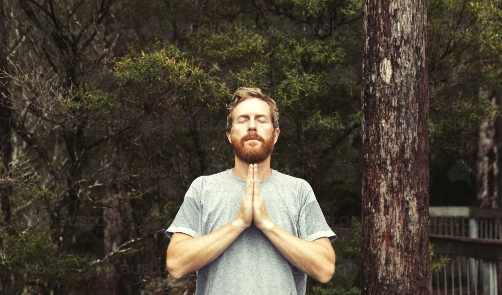 Bearded man praying amongst trees - Australian Stock Image