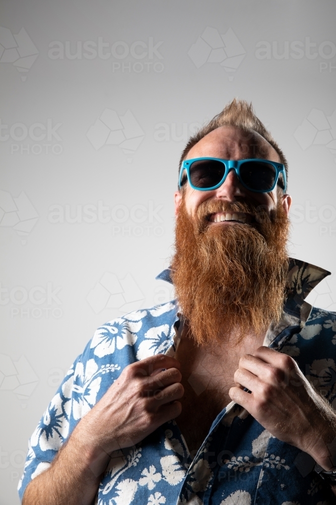 Bearded man with hawaiian shirt and sunglasses smiling at the camera - Australian Stock Image