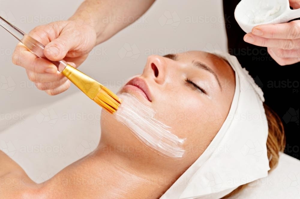 beautician uses a brush to apply cleanser during a facial - Australian Stock Image