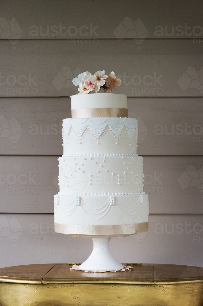 beautiful hollywood glam white wedding cake with pastel pink flowers and lots of piping - Australian Stock Image