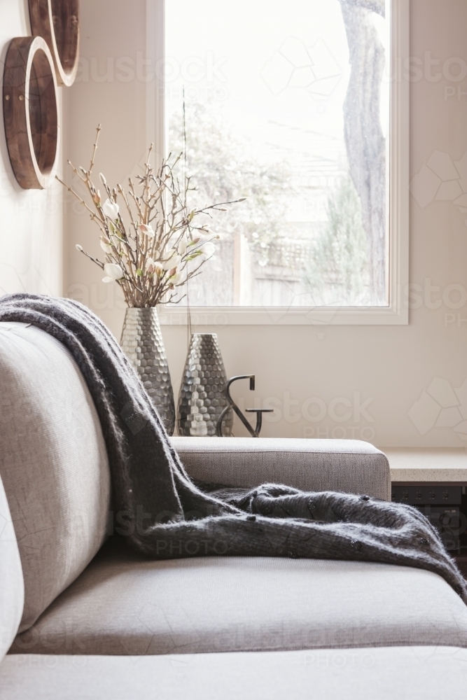 Beautiful inviting sofa with throw rug and soft window light behind - Australian Stock Image
