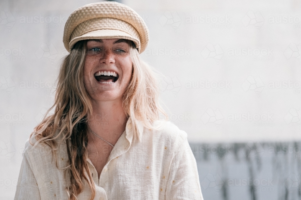 Beautiful laugh from a young woman wearing a cap. - Australian Stock Image