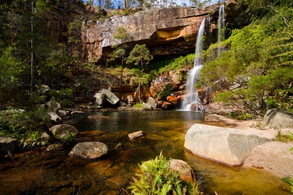 Beautiful scenic falls with colourful orange sandstone and green ferns - Australian Stock Image