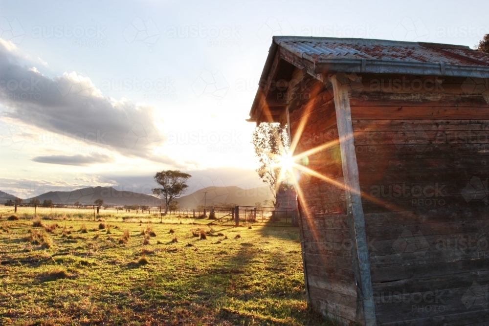 Beautiful sunrise over old outback dunny in a farm paddock - Australian Stock Image