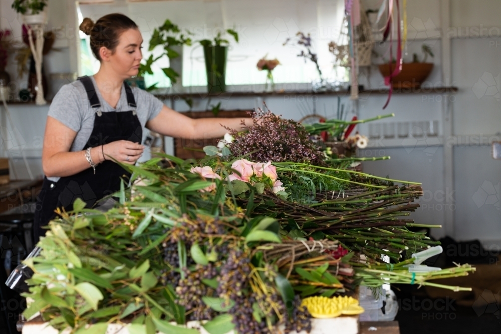 Beautiful young florist at work preparing flowers for an event - Australian Stock Image