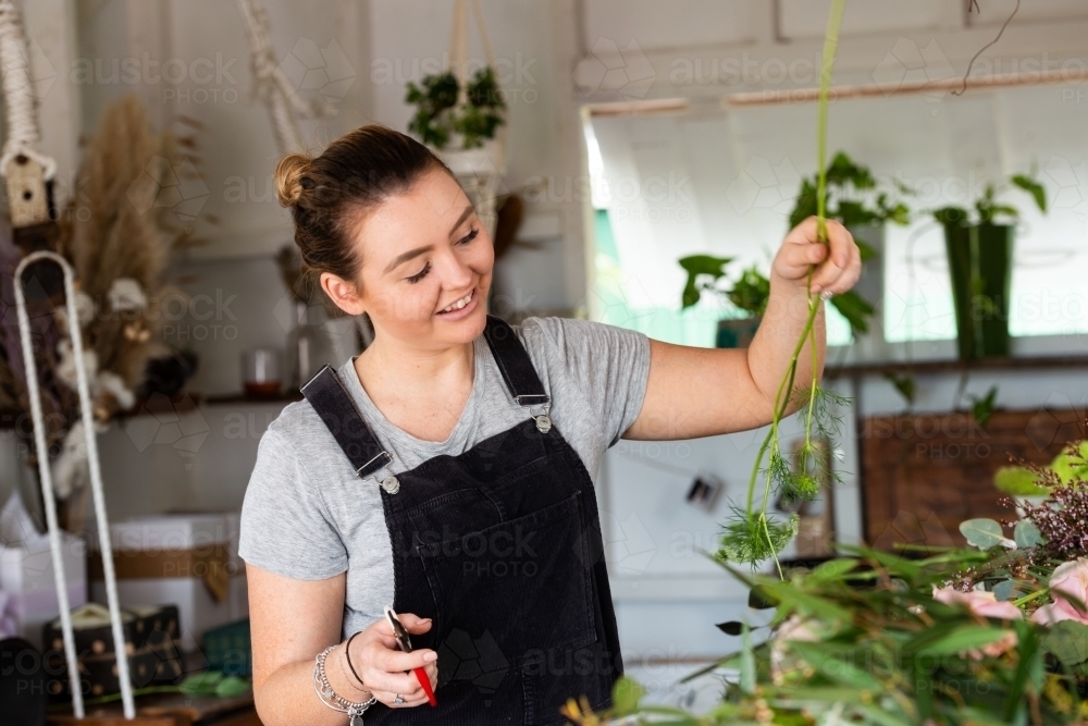 Beautiful young florist at work preparing flowers for an event - Australian Stock Image