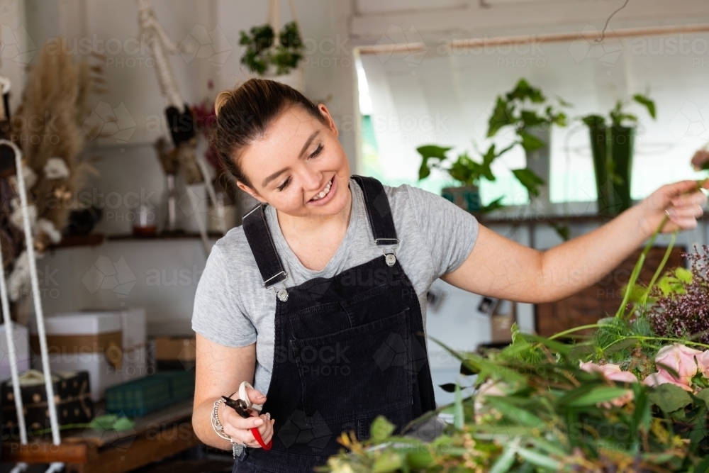 Beautiful young florist at work preparing flowers for an event - Australian Stock Image