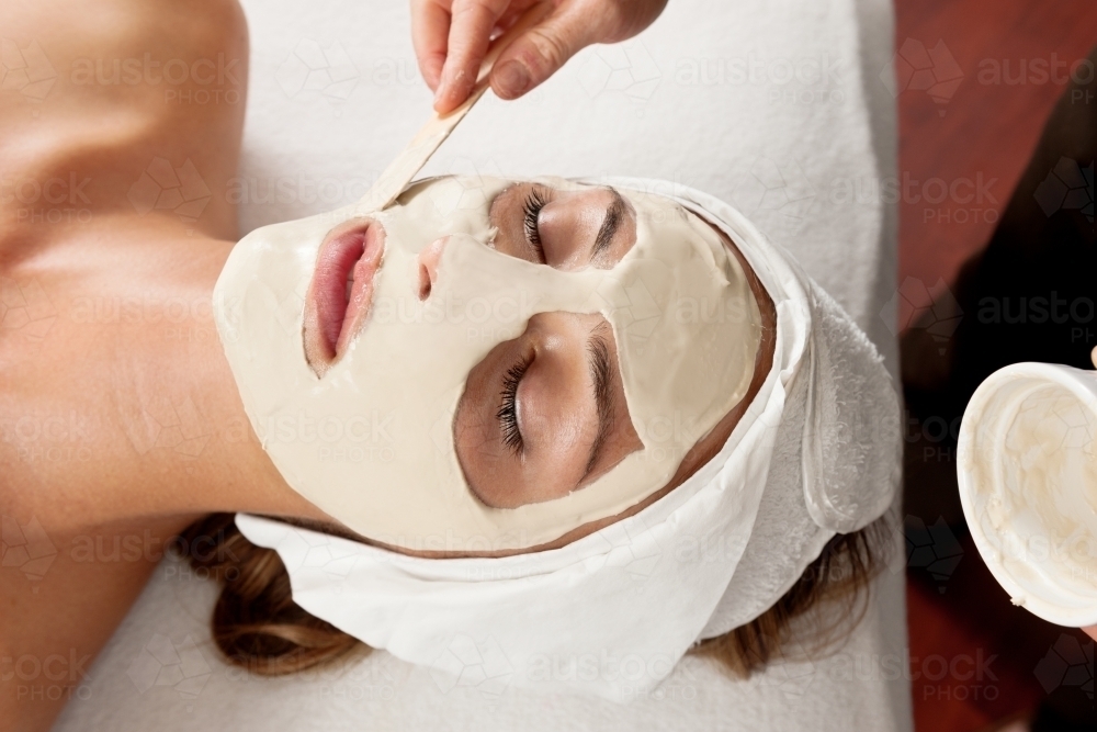 Beauty treatment, beautician applying a clay mask - Australian Stock Image