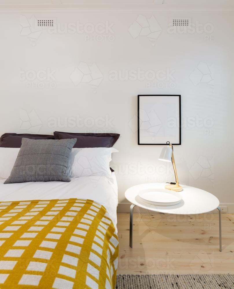 Bedroom decor details of yellow throw rug and bedside table with lamp - Australian Stock Image