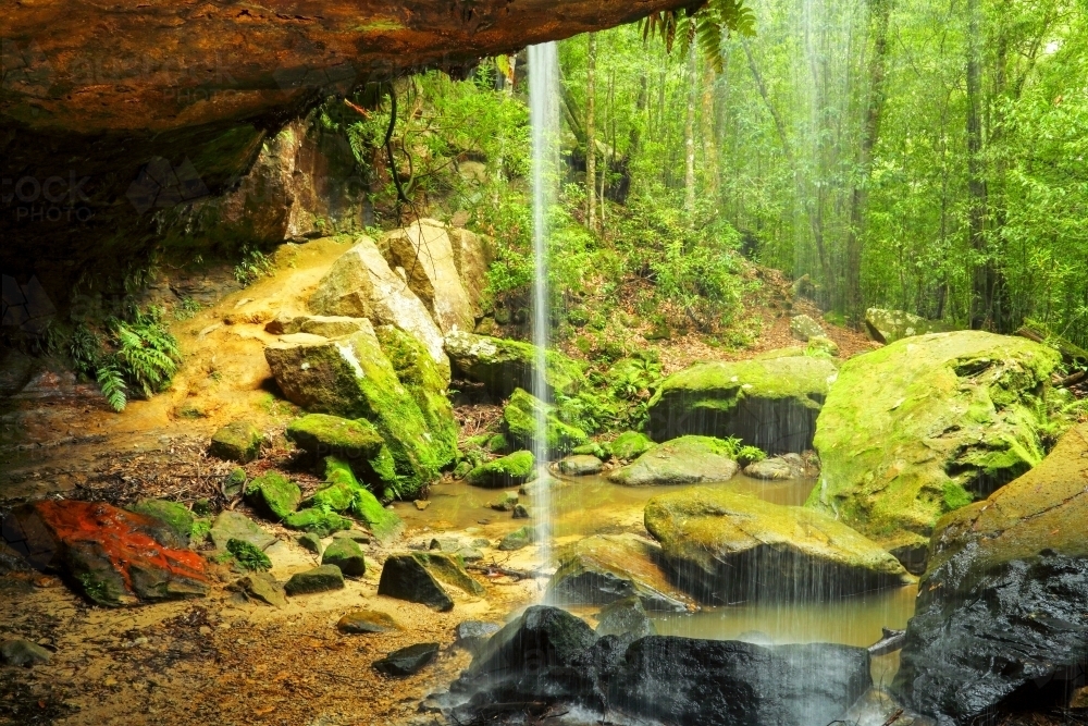 Behind the waterfall veil of Glow-Worm Nook Falls in the Blue Mountains of NSW - Australian Stock Image