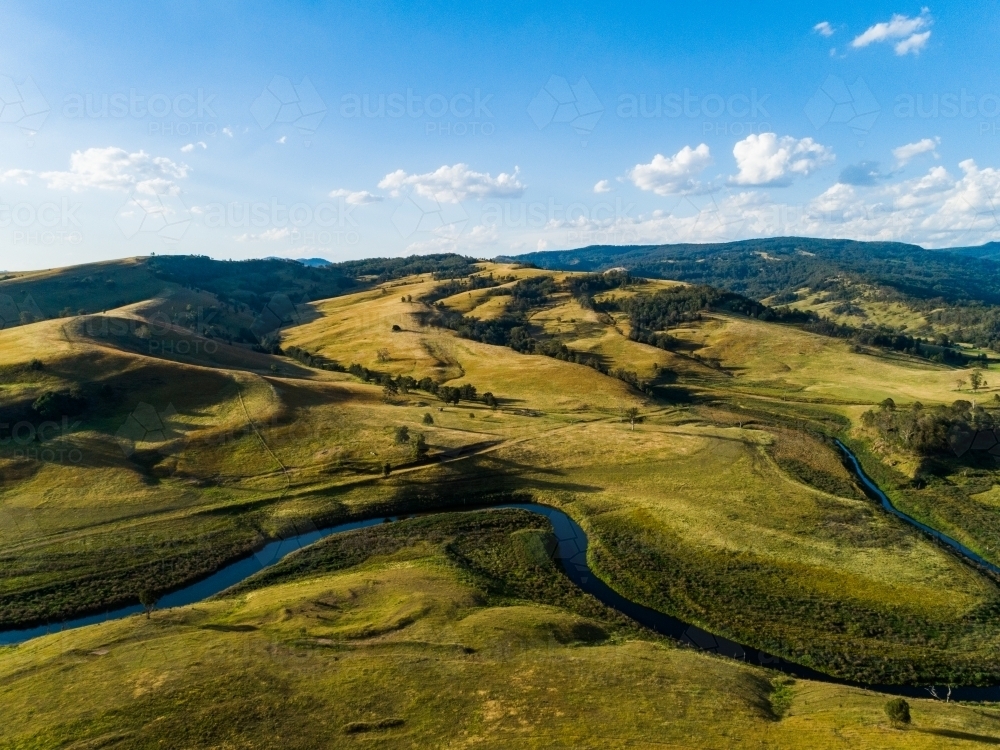 Bendy river winding through valley towards lake - Australian Stock Image