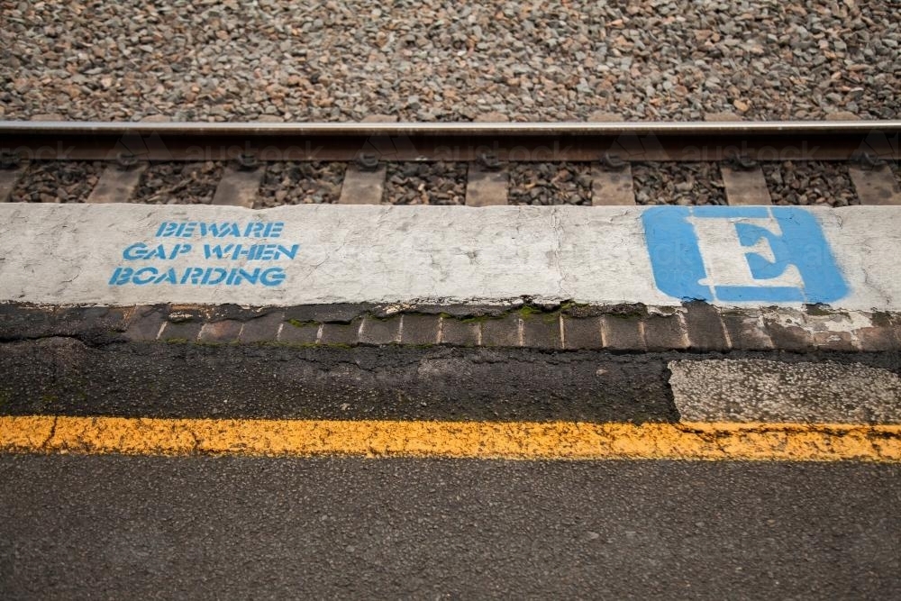 Beware gap when boarding sign next to train track - Australian Stock Image