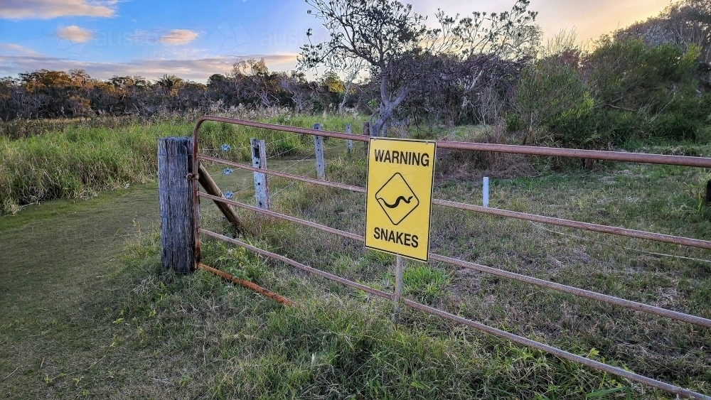 Beware of snakes yellow warning sign on gate in Australian bush - Australian Stock Image