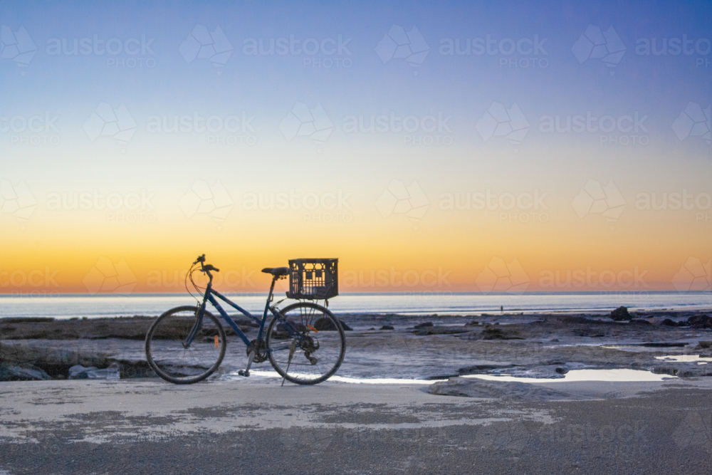 Bicycle parked on beach at sunset - Australian Stock Image
