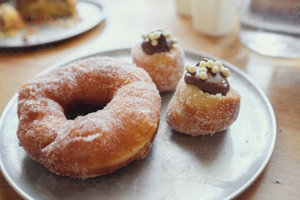 Big and small doughnuts on rustic plate - Australian Stock Image