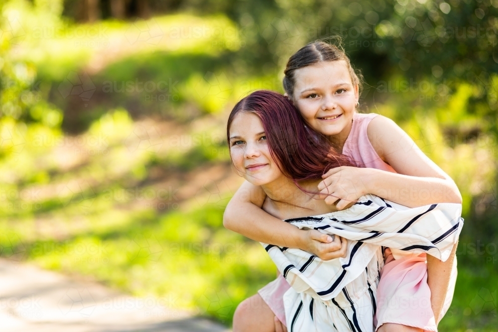 Big sister giving her little sibling a piggyback ride - Australian Stock Image