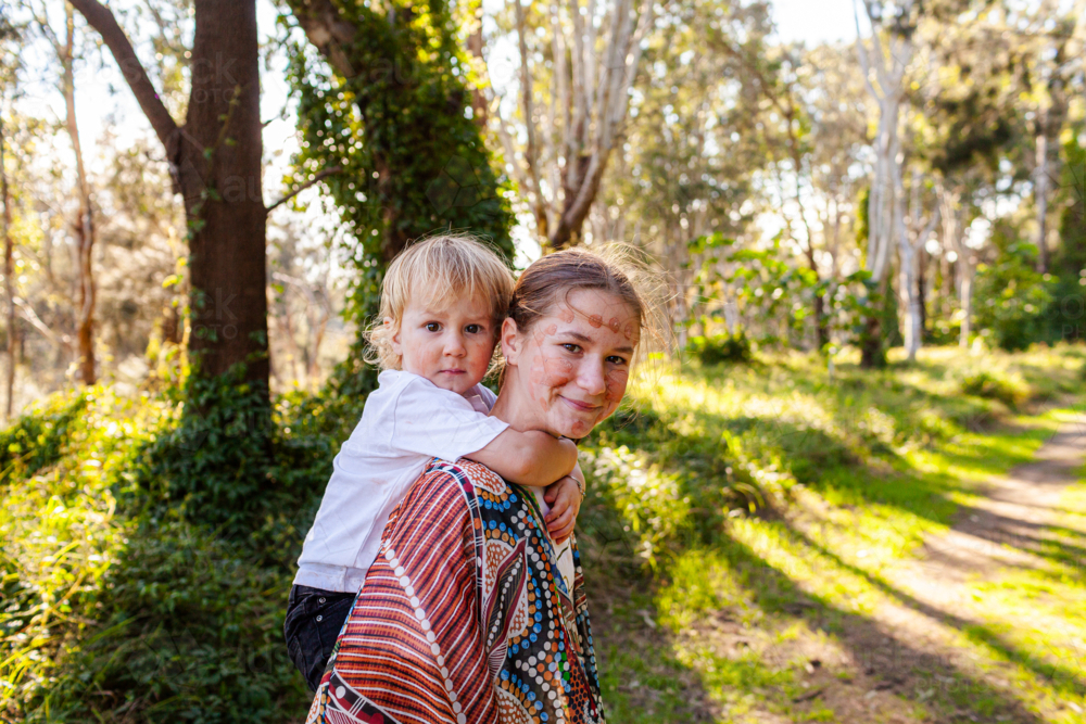 Big sister giving little brother a piggyback ride in nature - Australian Stock Image