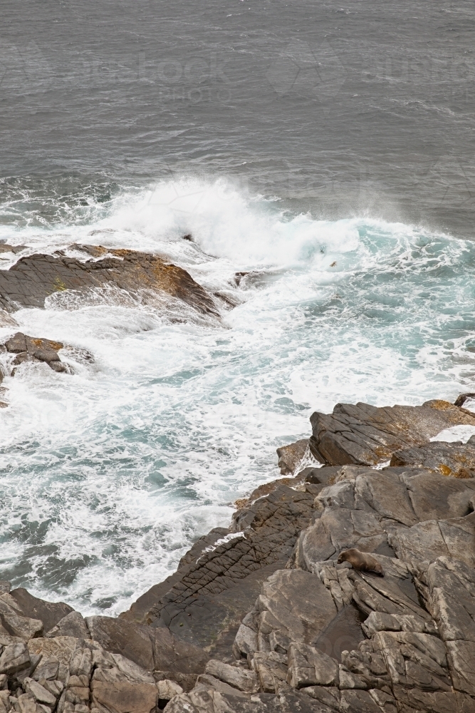 Big waves crashing against jagged coastal rocks - Australian Stock Image