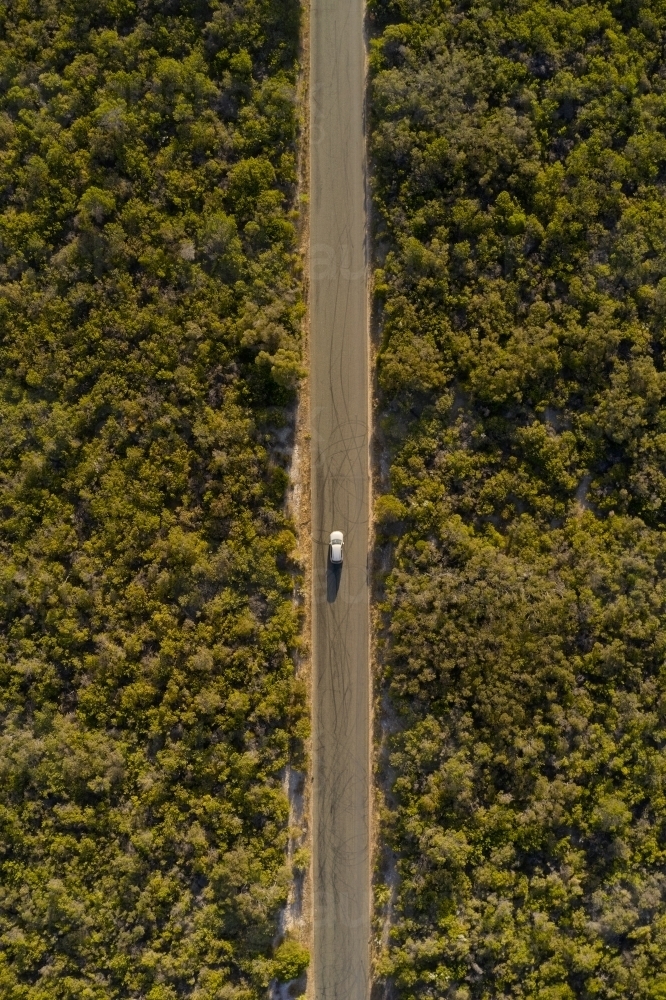 Bird's eye view of a small SUV driving on a coastal road towards a beach - Australian Stock Image