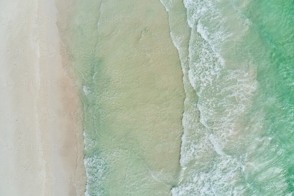 Bird's eye view of small waves washing ashore on a sandy beach in Perth, Western Australia - Australian Stock Image