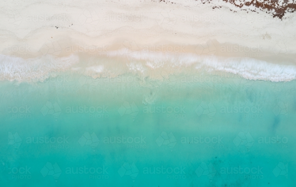 Bird's eye view of turquoise ocean waters lapping onto a sandy beach : Austockphoto Bird's eye view of turquoise ocean waters lapping onto a sandy beach - Australian Stock Image