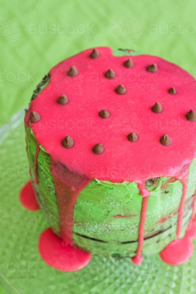 Birthday cake in watermelon theme, green icing with hot pink dripping ganache down side of cake - Australian Stock Image