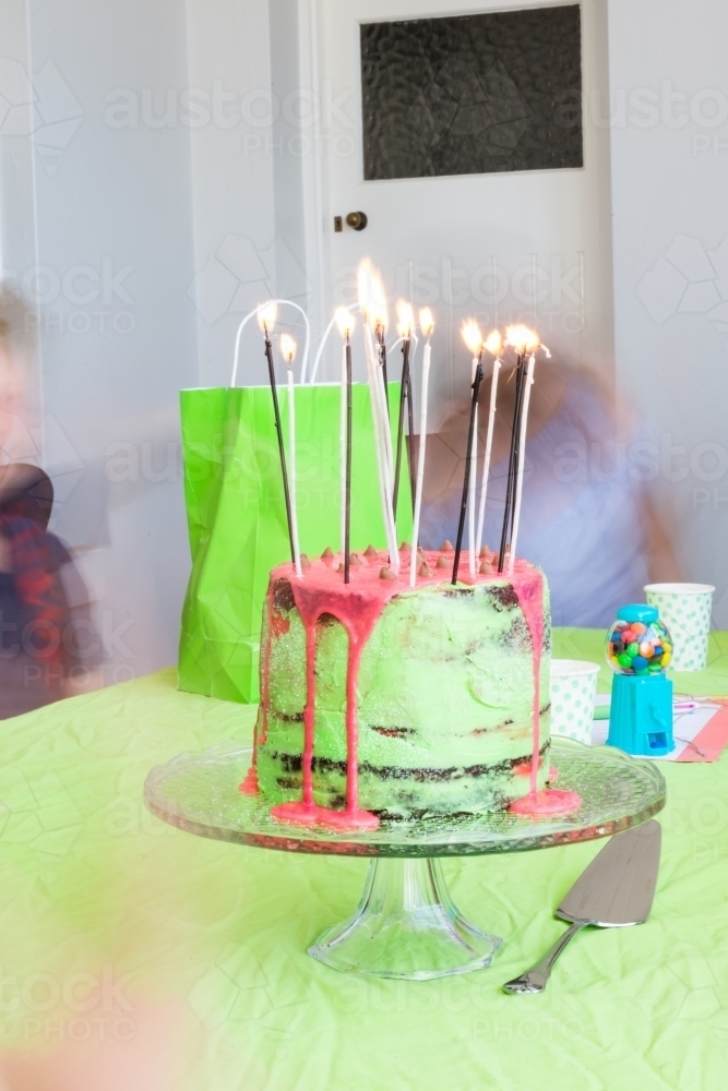 birthday cake with candles and blurred kids in the background - Australian Stock Image