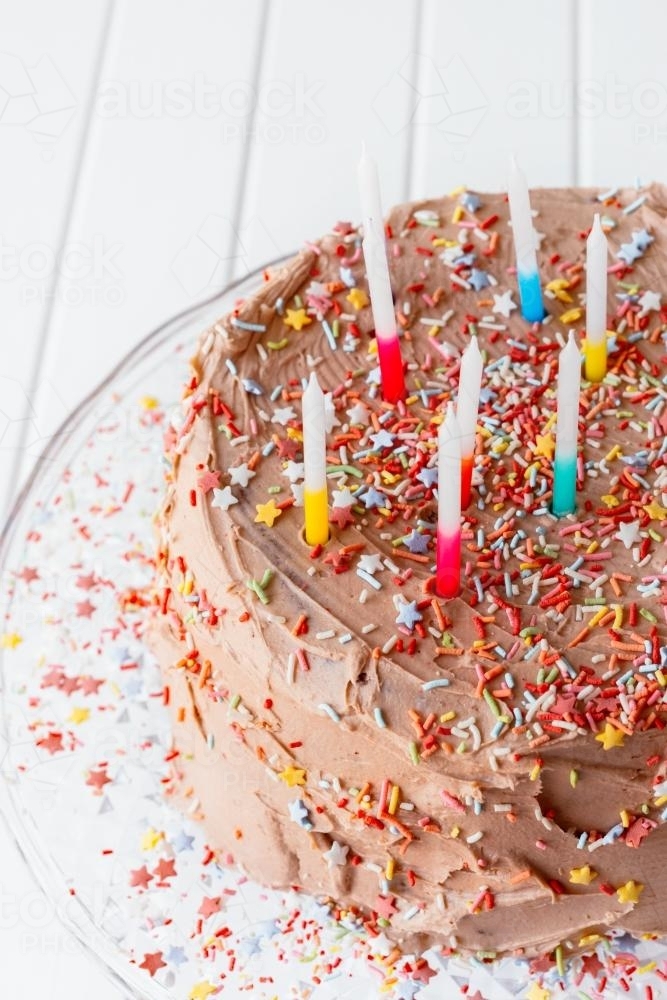 birthday cake with chocolate icing, sprinkles and candles - Australian Stock Image
