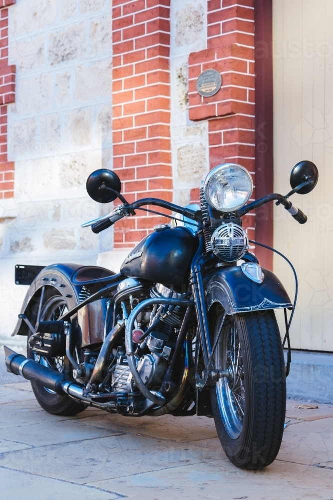 Black classic motorcycle parked in front of a heritage building - Australian Stock Image