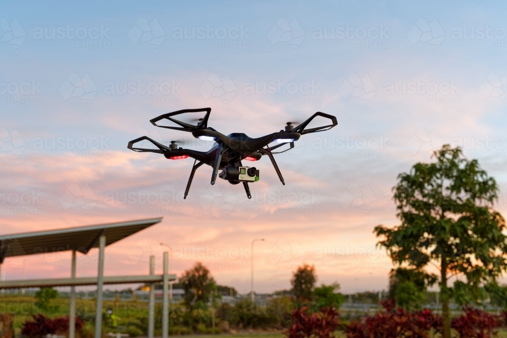 Black Drone, UAV, RPAS at sunset in an empty park - Australian Stock Image