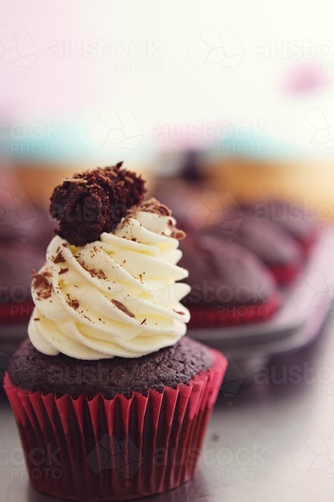 Black forest iced cupcake with blurred tray in background - Australian Stock Image