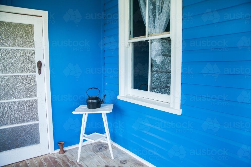 Black kettle on deep blue country homestead verandah - Australian Stock Image