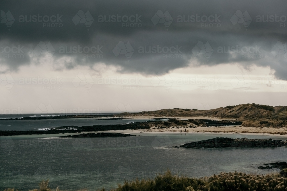 Black storm clouds roll in over a beach. - Australian Stock Image