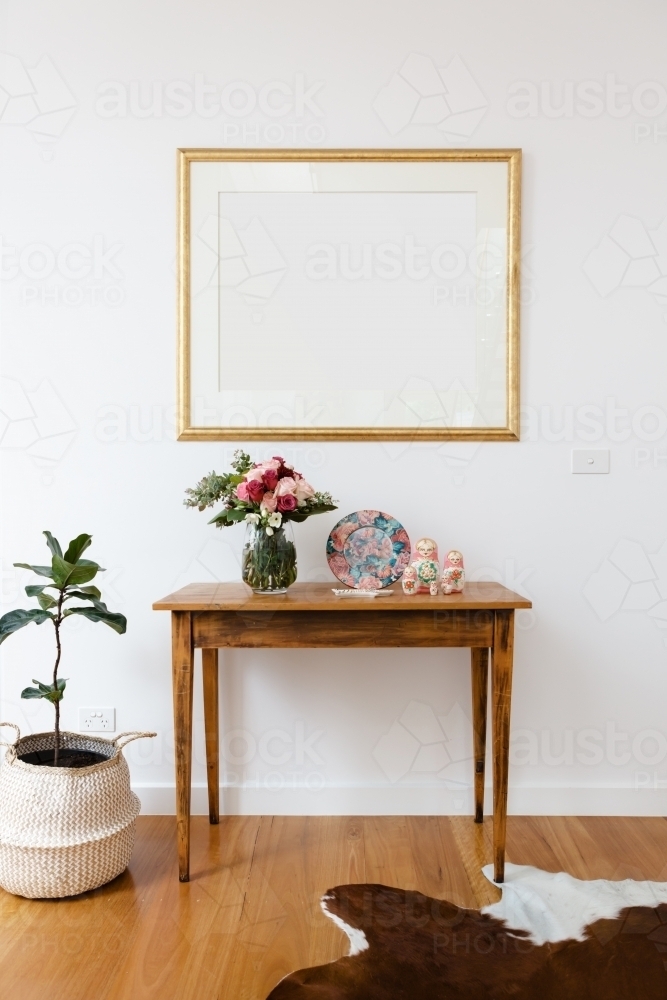 Blank picture frame above a side table with flowers and pot plant - Australian Stock Image