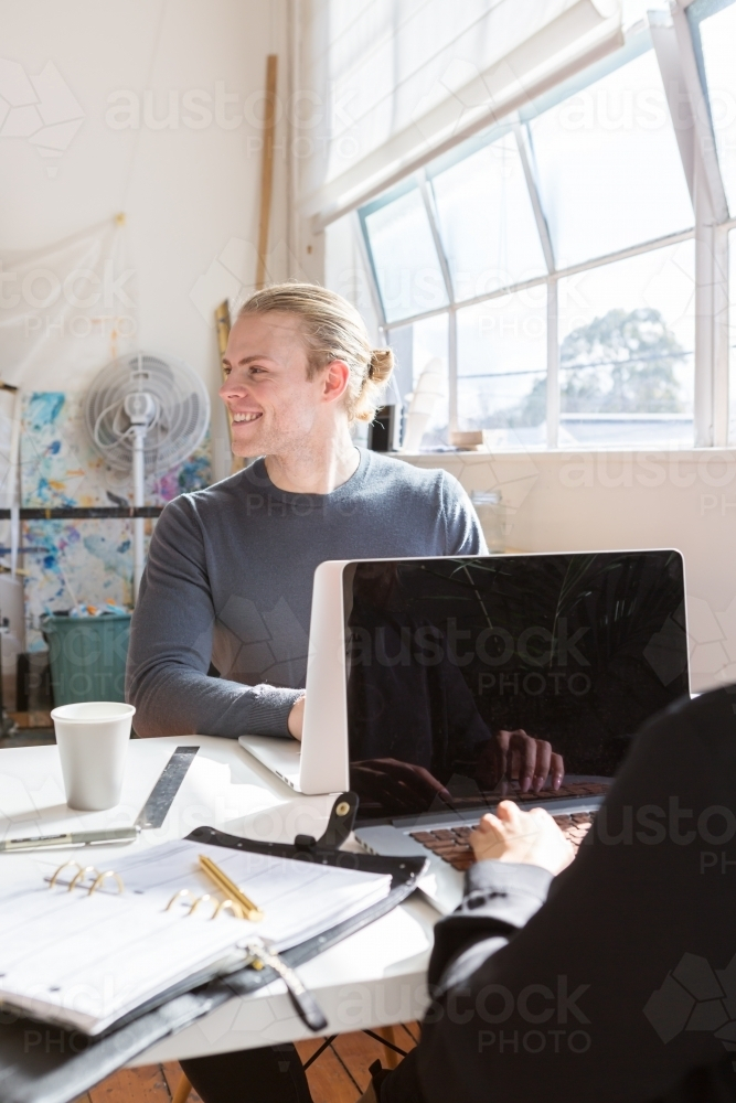 Blond guy at work looking away from his desk - Australian Stock Image