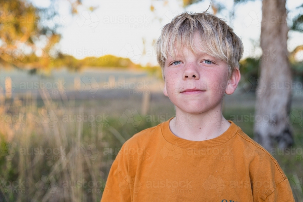 Blond scruffy boy on farm looking at camera - Australian Stock Image